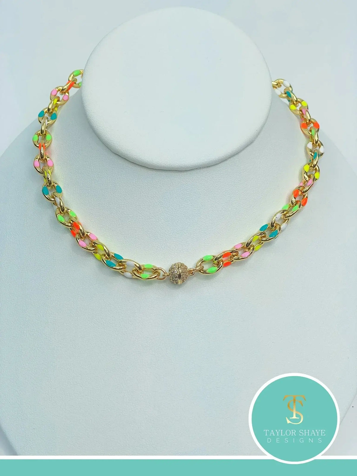 Rainbow-colored Ezzy Choker Necklace by Taylor Shaye, featuring a 16-inch chain with a magnetic clasp, displayed on a jewelry stand.