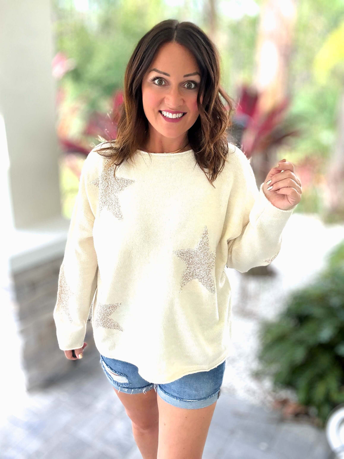 Woman wearing Golden Glam Sweater with star design and cream color, styled with denim shorts, showcasing a cozy and stylish look.