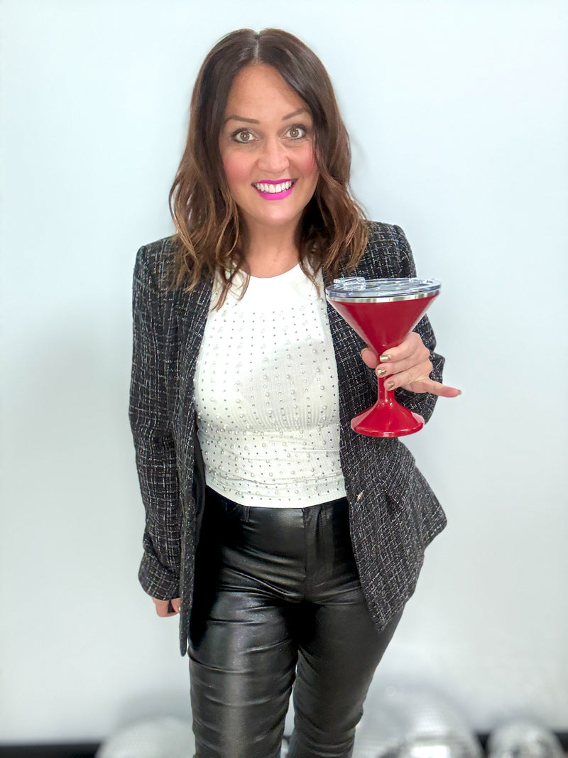 Woman wearing City Lights Blazer, holding a red cocktail, exuding confidence and style in black leather pants and a white top.