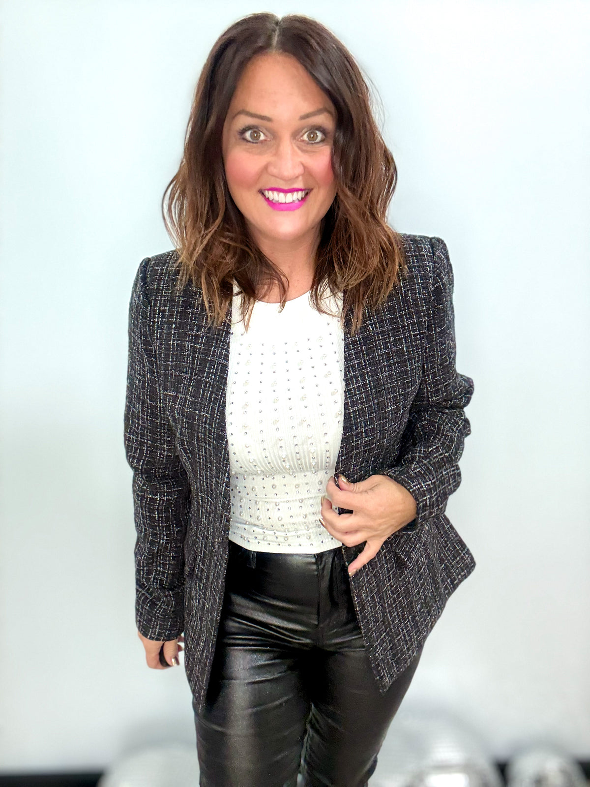 Woman wearing City Lights Blazer with shimmer detail, paired with a white top and black pants, exuding confidence and style.